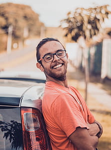 Man in Orange T-shirt Leaning on a Car thumbnail