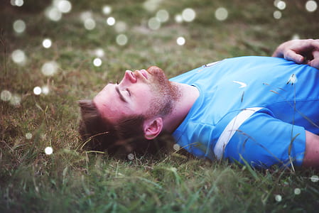 man lying down on grass during daytimer thumbnail