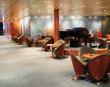 brown grand piano on stage surrounded by chairs and tables thumbnail
