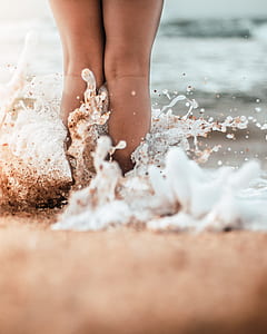 person standing on seashore with water splash at beach thumbnail