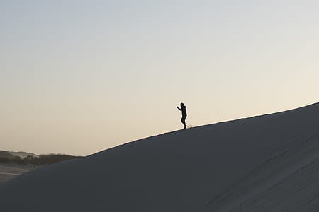person standing on the top of a hill during sunset thumbnail