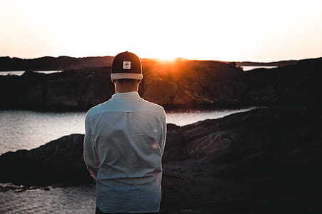 man wearing white shirt standing during daytime facing golden hour thumbnail