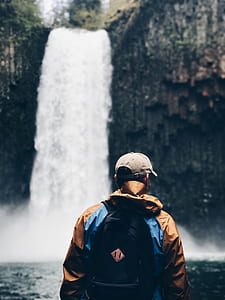 man stainding in front of a waterfall thumbnail