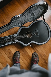 person standing near black acoustic guitar in black case thumbnail