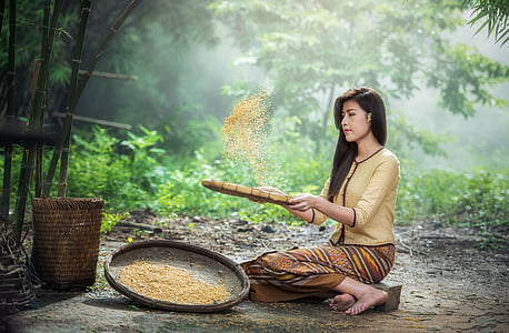 woman wearing white long-sleeved shirt and brown and yellow skirt holding brown wicker basket thumbnail