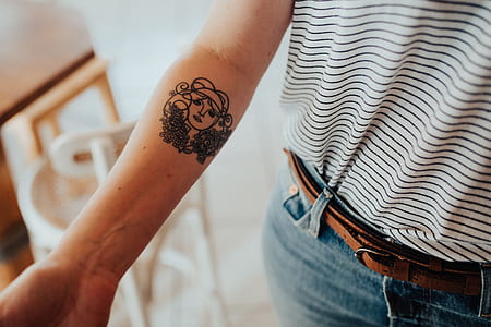 person with woman's face arm tattoo thumbnail