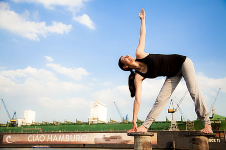 woman holding her foot exercising on gray metal bar during daytime thumbnail