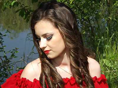 focus photography of woman wearing off-shoulder top near body of water and green tree thumbnail