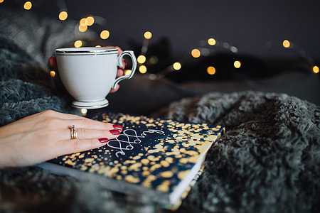 Young woman at home reading Hygge book and drinking thumbnail