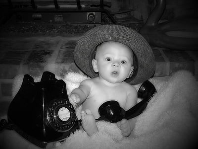 baby sitting on fur rug beside rotary telephone on grayscale photography thumbnail