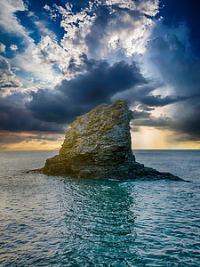 brown and gray rock formation on ocean under white clouds during daytime thumbnail