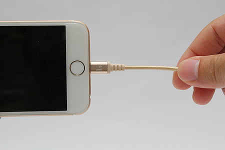 person holding brown lightning cable connected to gold iPhone 6 with turned-off screen thumbnail