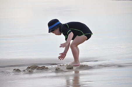 toddler playing with sand near water thumbnail
