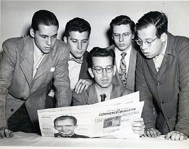 grayscale photography of five men looking at newspaper held by sitting man wearing eyeglasses thumbnail