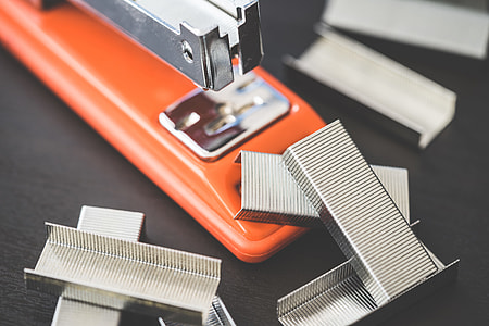 Red Office Stapler and Pile of Copper Office Staples thumbnail