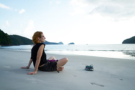 woman sitting on gray sand near the sea thumbnail