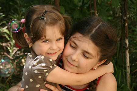 two girls hugging beside trees thumbnail
