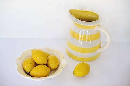 five yellow lemonades on white ceramic bowl near white ceramic pitcher thumbnail