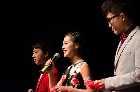 woman holding microphone in between two men with black background thumbnail