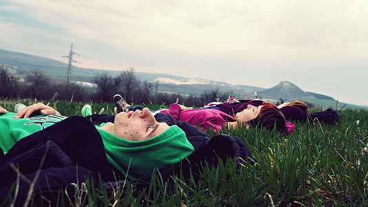 four person laying on a green grass field thumbnail
