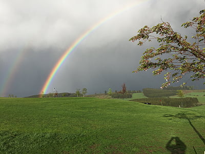 rainbow passing through clouds on top of hill thumbnail
