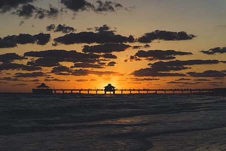 silhouette of beach dock during golden hour thumbnail