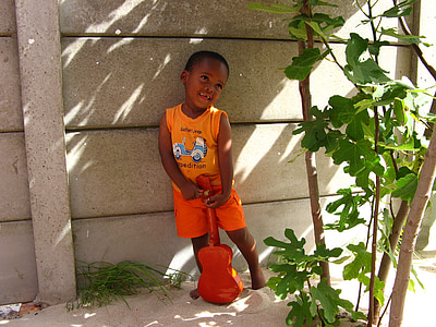 boy holding ukulele leaning on wall thumbnail