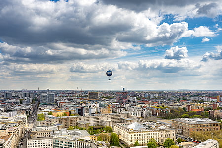 hot air balloon floating above buildings thumbnail
