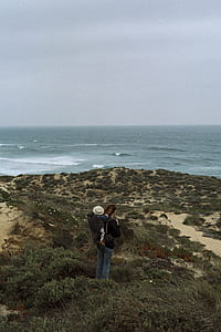 photo of woman carrying baby at her back watching beach waves thumbnail