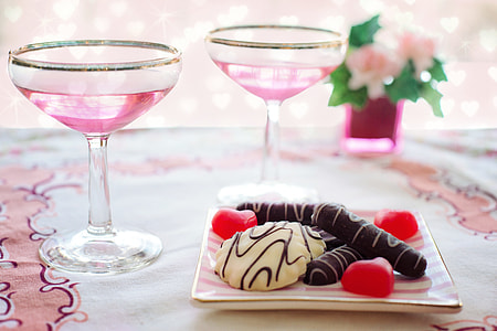 two wine glass beside vanilla and chocolate coated biscuit on plate thumbnail