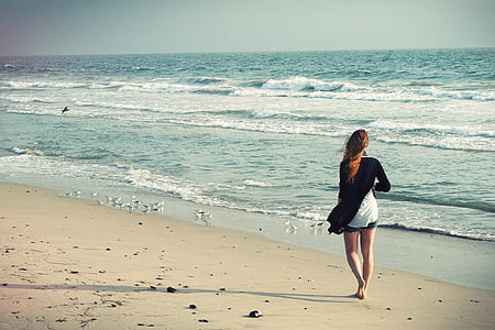 woman walking beside of beach during daytime thumbnail
