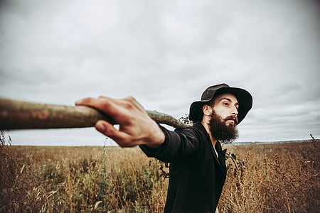 man holding brown stick on brown grass during daytime thumbnail