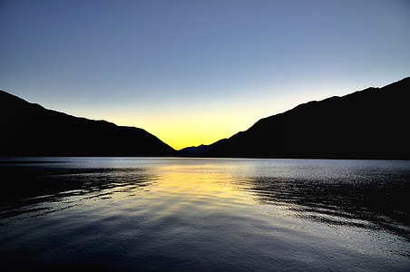 golden hour photo of sun between two mountains in front of body of water photography thumbnail