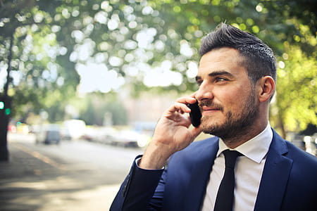 A bearded caucasian man in blue formal suit calling on his mobile phone in outdoors thumbnail
