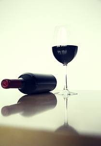 wine bottle and glass placed on beige surface thumbnail