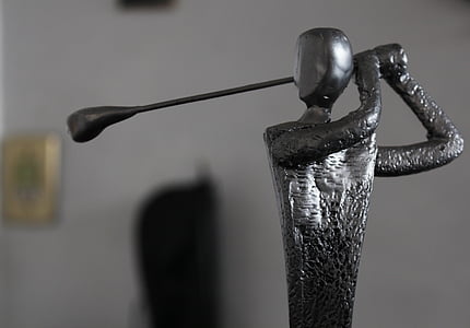 macro photography of figure holding gold club thumbnail