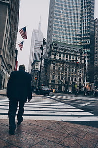 Man Walking on Road Wearing Suit Jacket and Dress Pants Beside High-rise Concrete Buildings thumbnail