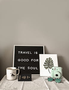 photo of mug, quote print board, passport, sunglasses, and instant camera on table thumbnail