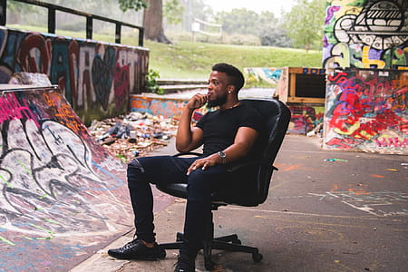 Man Wearing Black Crew-neck Shirt Sitting on Leather Rolling Chair thumbnail
