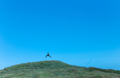 person jumping on top of green field thumbnail