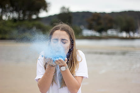 woman blowing blue colored powder thumbnail