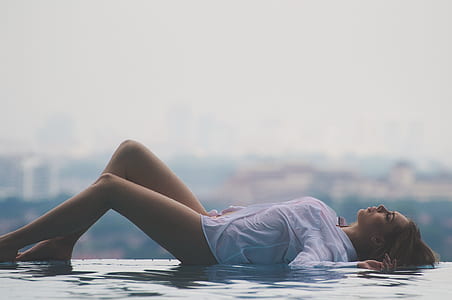 woman lying on side of swimming pool during daytime thumbnail