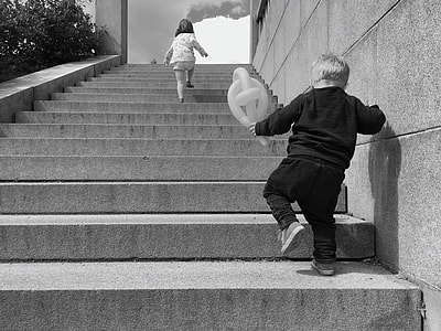 boy holding balloon walking on stairs grayscale photo thumbnail