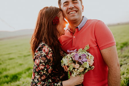 woman standing near man smiling together under sun on green grass at daytime thumbnail