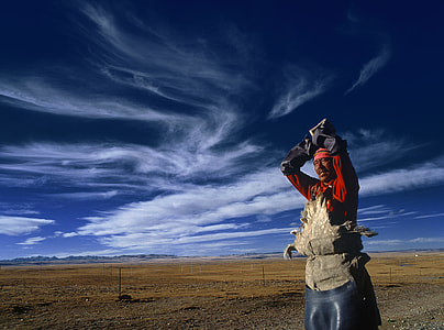 man wearing red suit standing outside below blue sky thumbnail