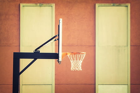 right side-view photo of white basketball hoop near orange concrete wall thumbnail