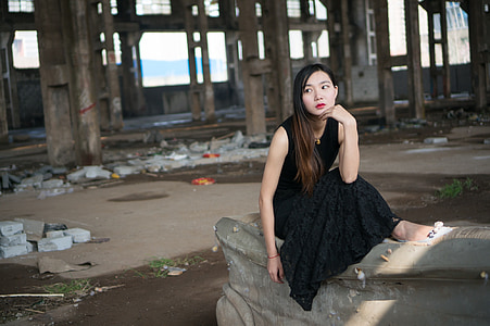 woman in black sleeveless long dress sitting on the sofa inside abandon building thumbnail