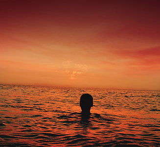 person in body of water during golden hour thumbnail