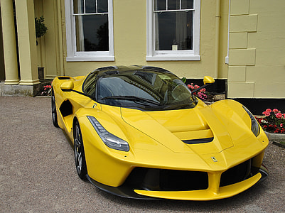 yellow sports car parked beside house wall thumbnail