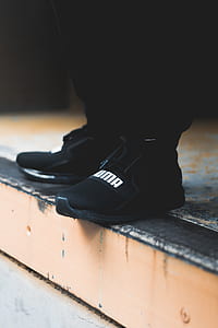 person wearing pair of black-and-white Puma shoes thumbnail
